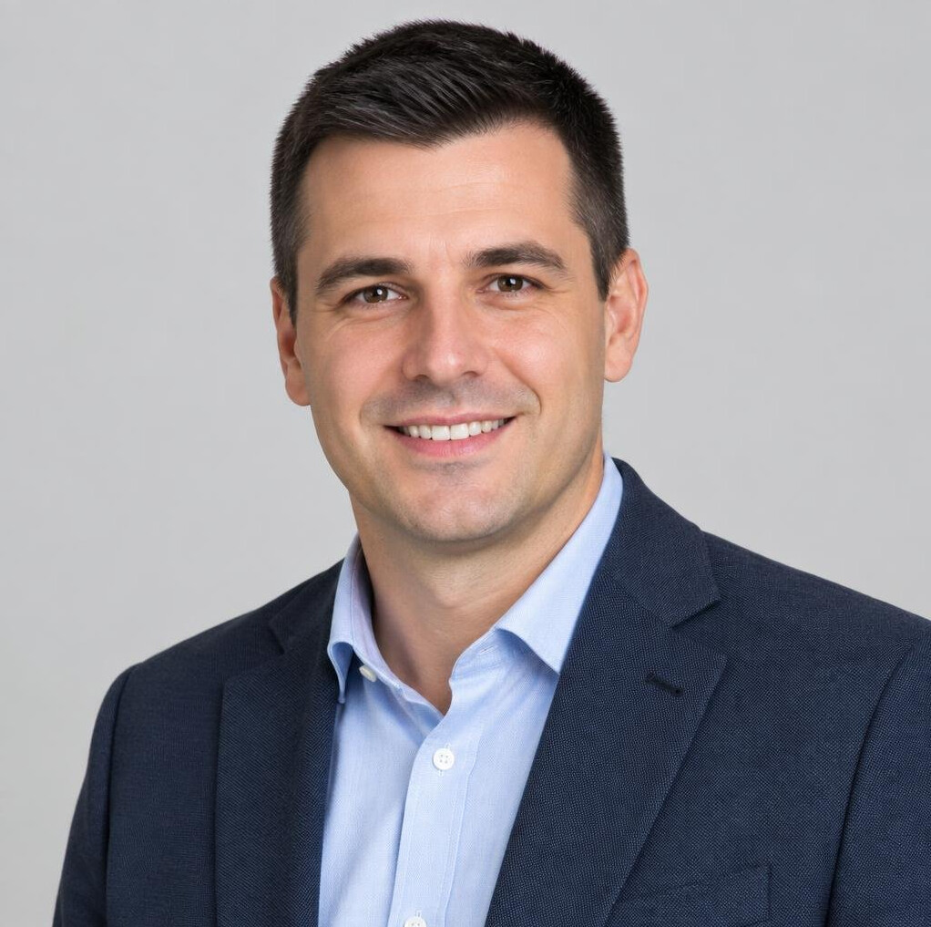Studio portrait of a smiling man with short dark hair in business casual clothing