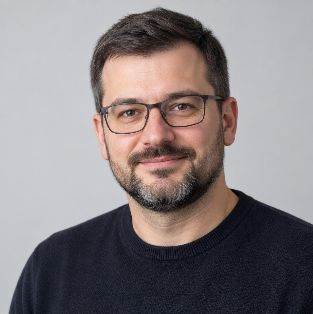 Studio portrait of a man with glasses and a beard in a dark sweater